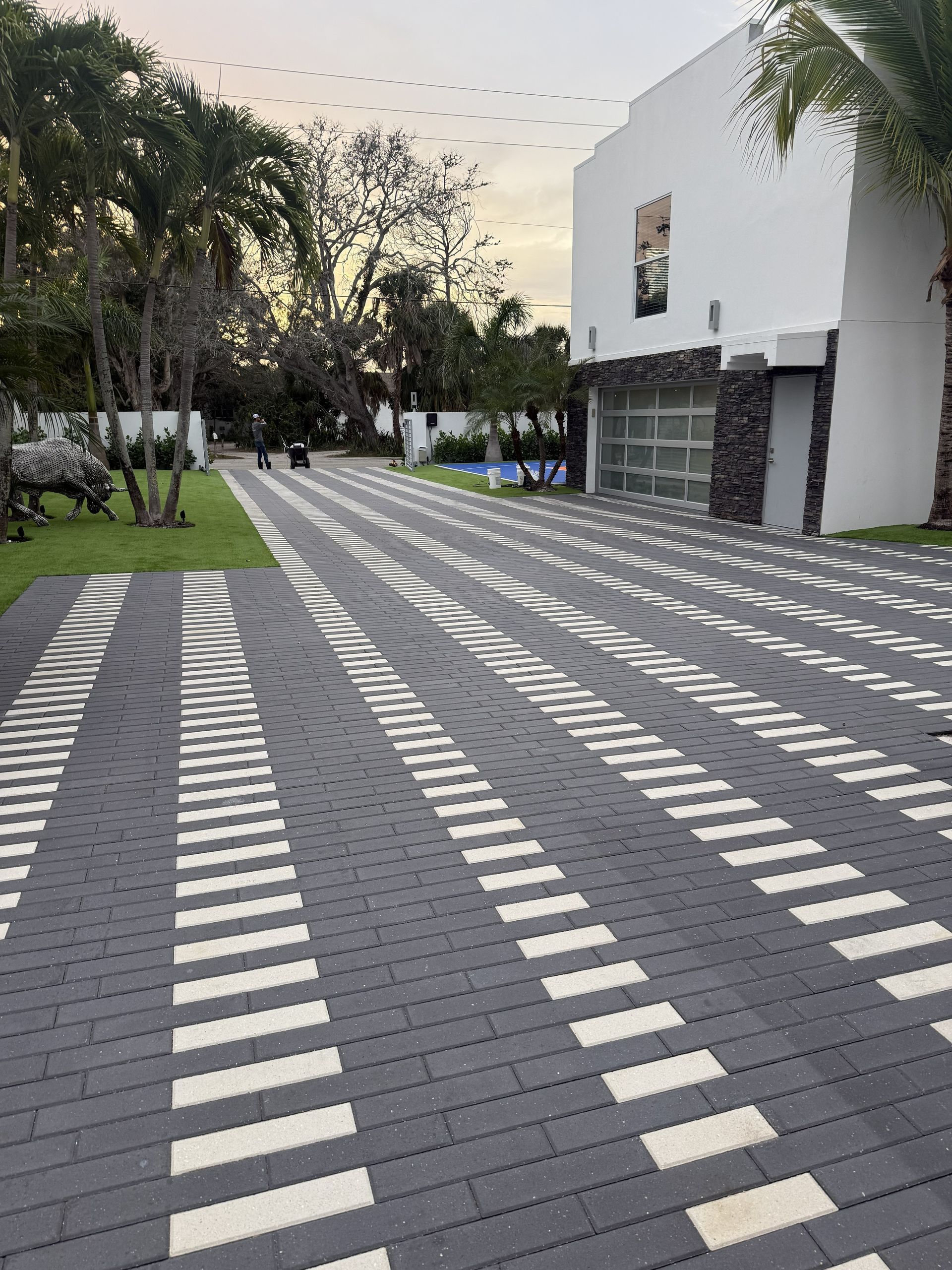 Modern tiled walkway in a landscaped courtyard beside a white building at dusk