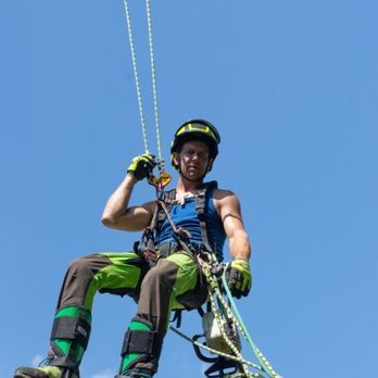 A man is sitting on a rope with a blue sky in the background