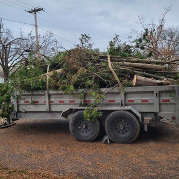 A dump truck filled with lots of wood is parked in a driveway.