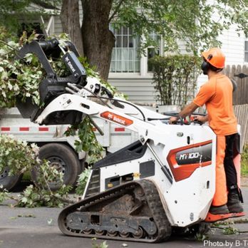 A man is operating a bobcat tractor on a street