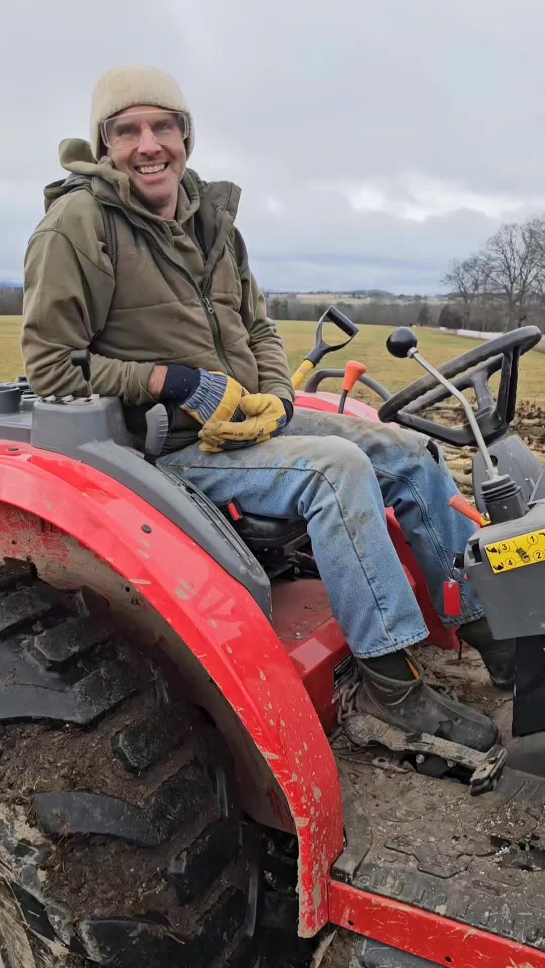 A man is sitting on a red tractor in a field.