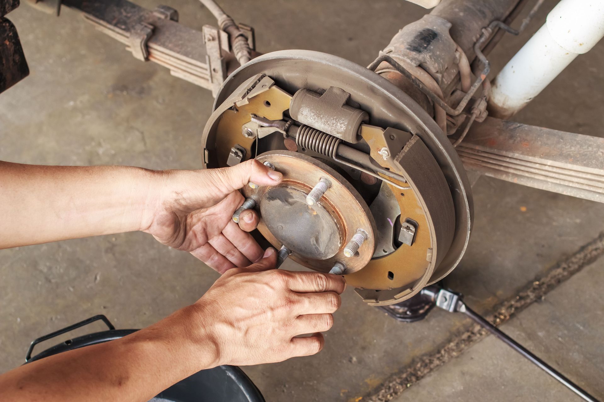 Person removing brake pads from a car's rear wheel. Close-up view, hands visible.
