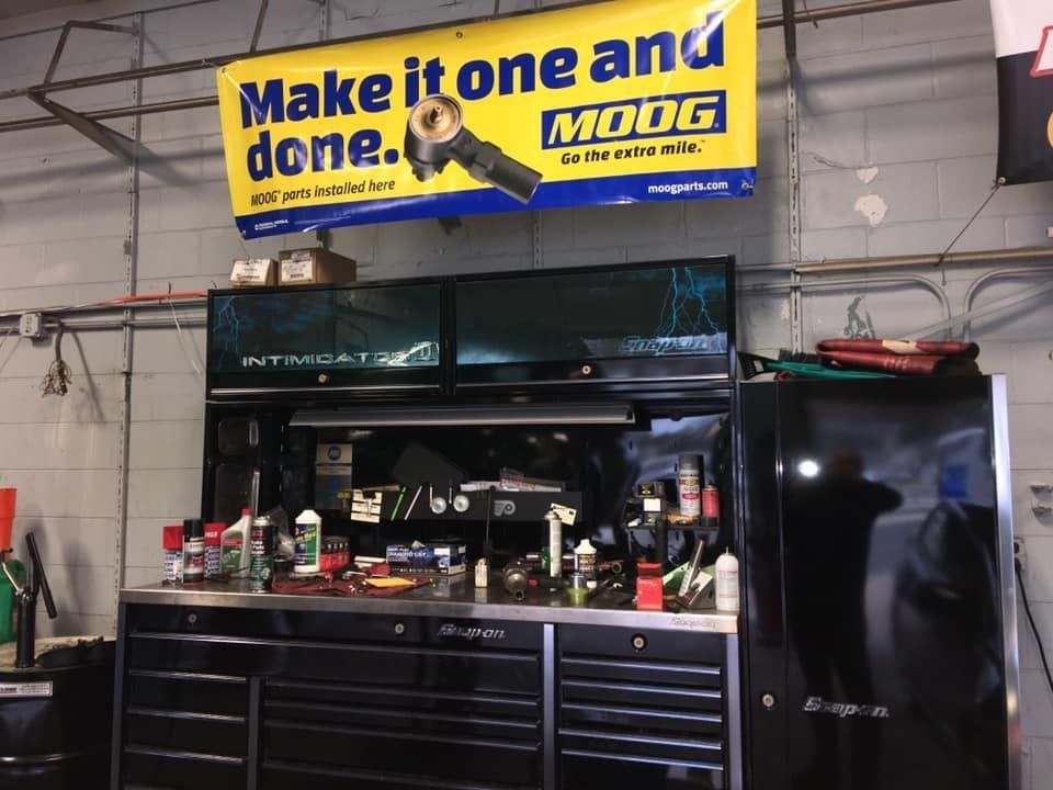 A mechanic's workspace with a black toolbox, tools, and a 