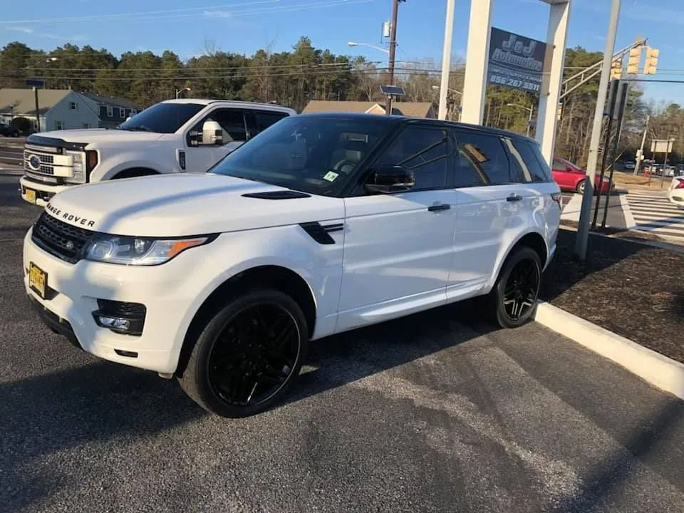 White Range Rover SUV with black rims parked on a paved lot.