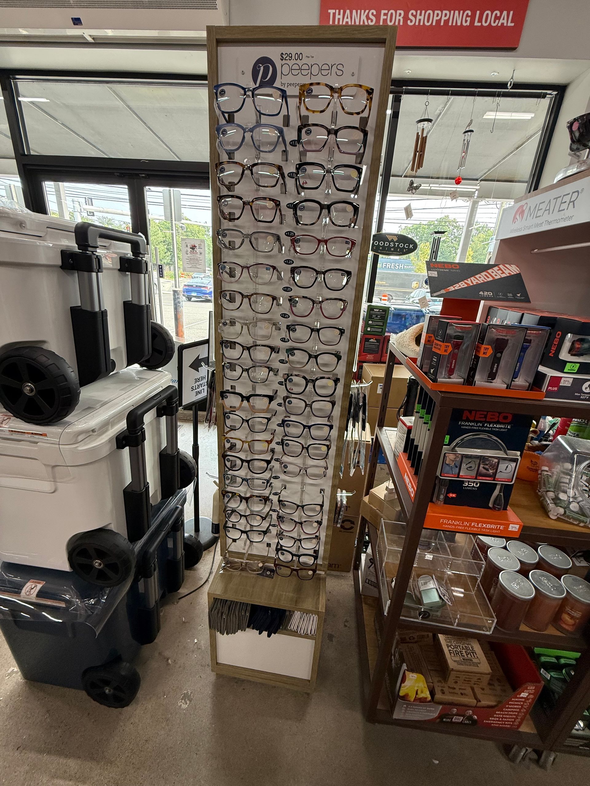 A tall display of eyeglasses stands in a retail store. The glasses are arranged on a white frame.