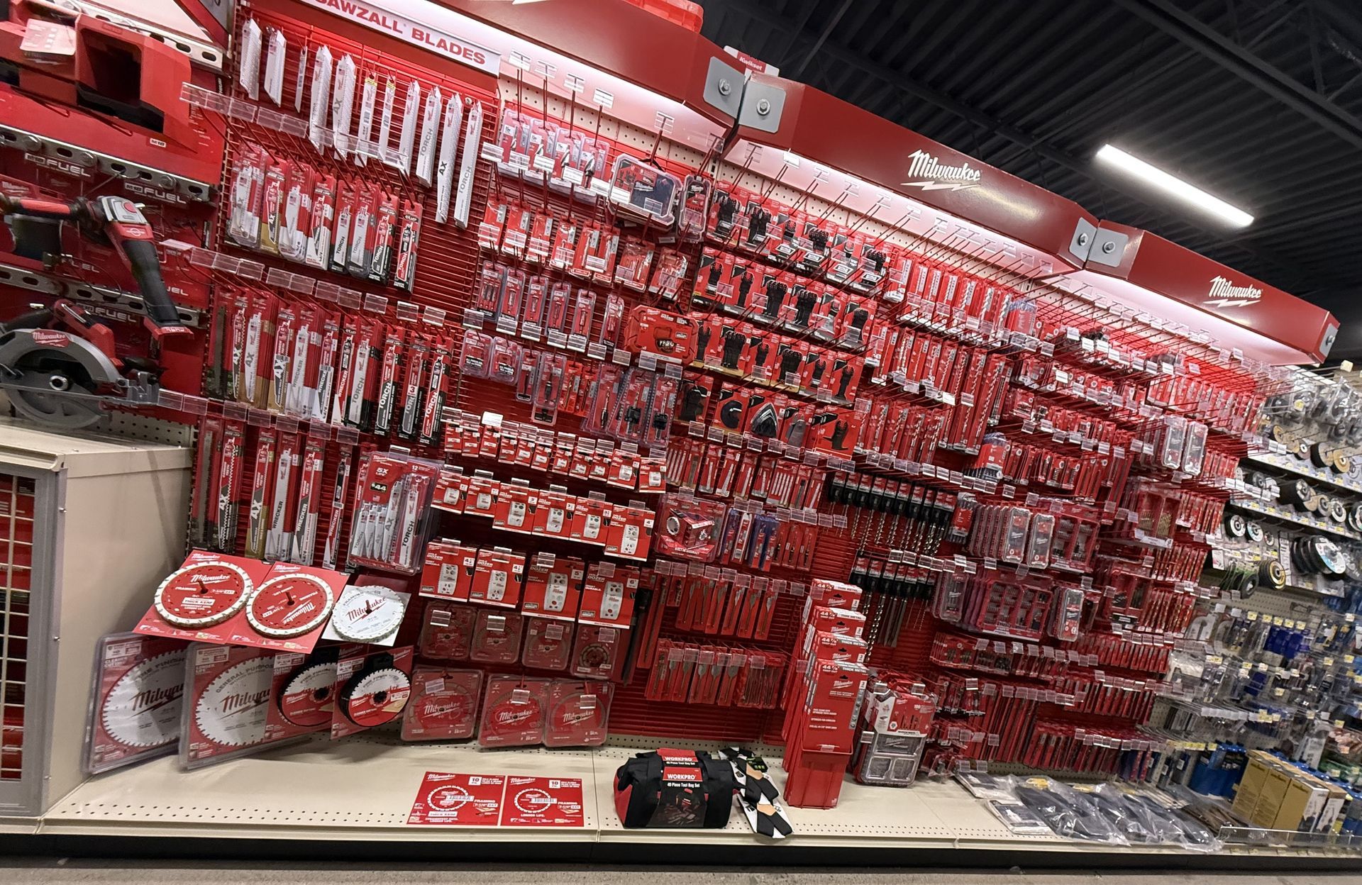 A wall display in a hardware store featuring various Milwaukee power tool accessories in red packaging.