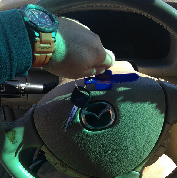 Hand placing a blue charging cable into a car’s dashboard port beside a Mazda steering wheel
