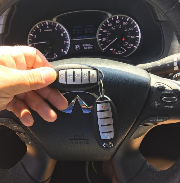 Hand holding a car key fob in front of a Mitsubishi steering wheel and dashboard