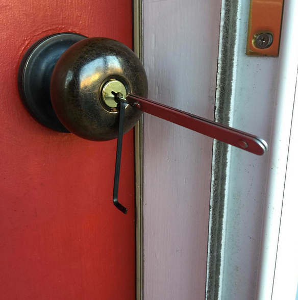 Close-up of a brass doorknob with a key inserted in a red door