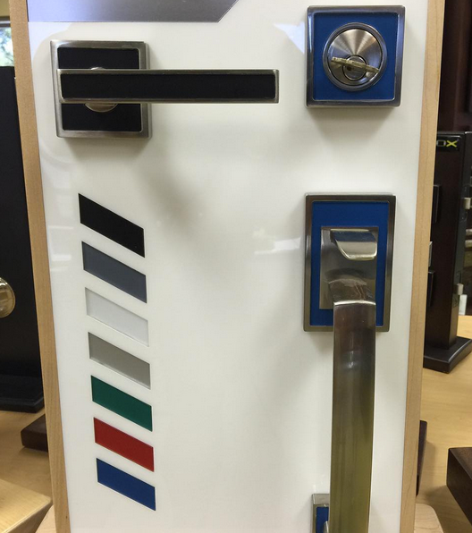 Modern door hardware display with black lever, chrome knobs, and color swatches on a white panel