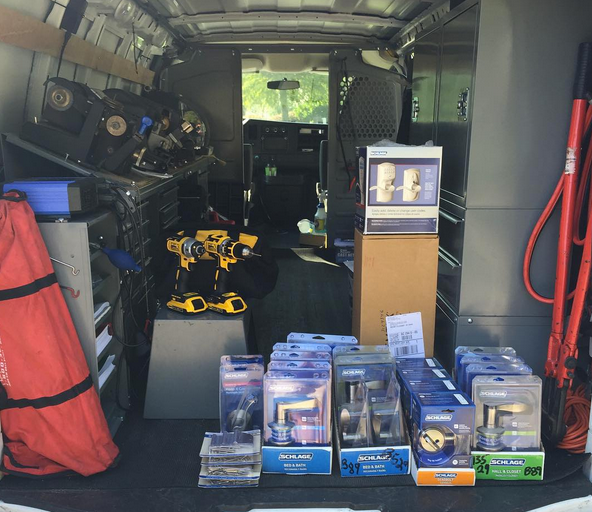Van interior packed with electronics, yellow drone, and boxed items on shelves and floor.