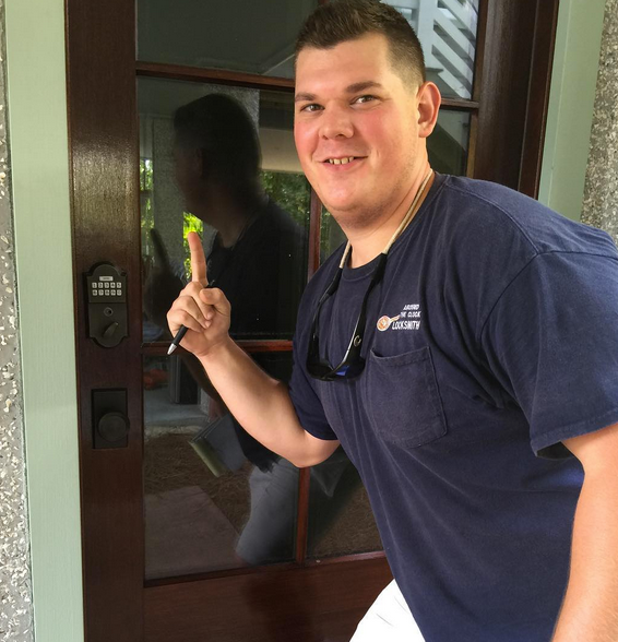 Man smiling at a front door while holding a colorful key on a porch
