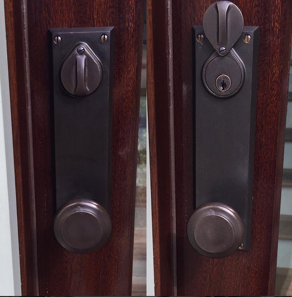 Two dark metal door latches on stained wood doors, one locked and one unlocked.