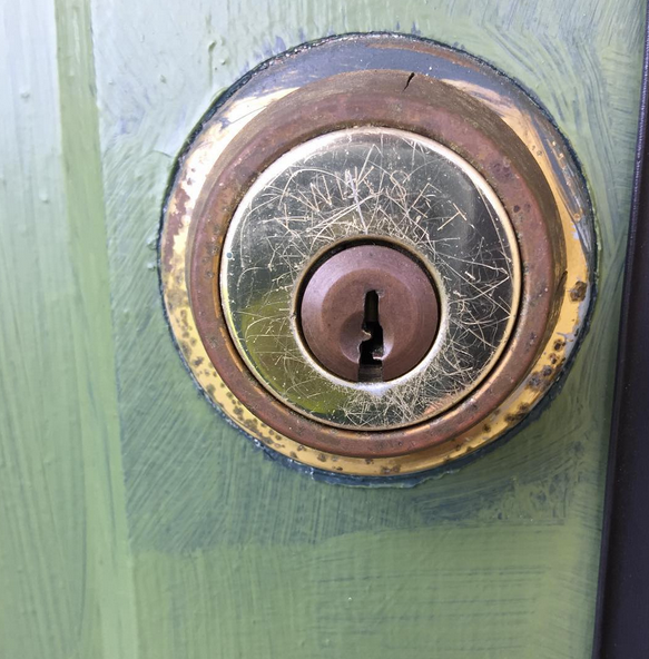 Close-up of a brass door lock on a green-painted door.