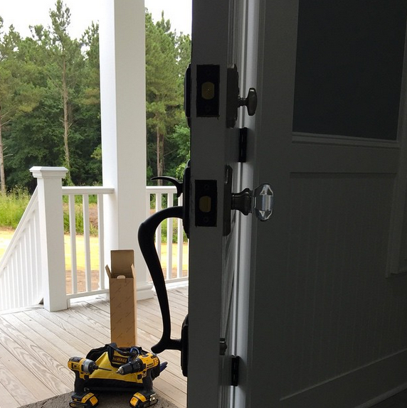 Open front door with porch view and a yellow tool bag on the wooden floor.