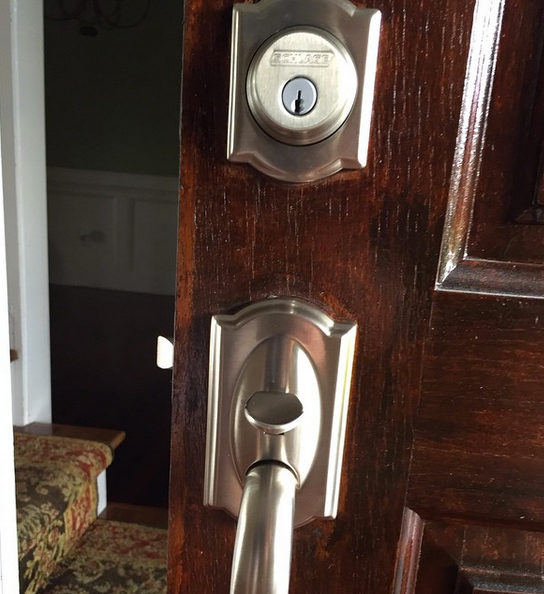 Close-up of a dark wooden door with a silver deadbolt and handle lock.