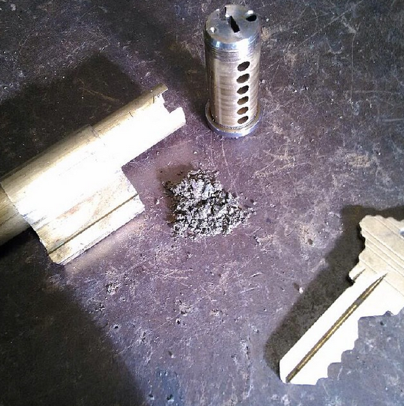 Metal machine parts and a small pile of shavings on a dark workbench.