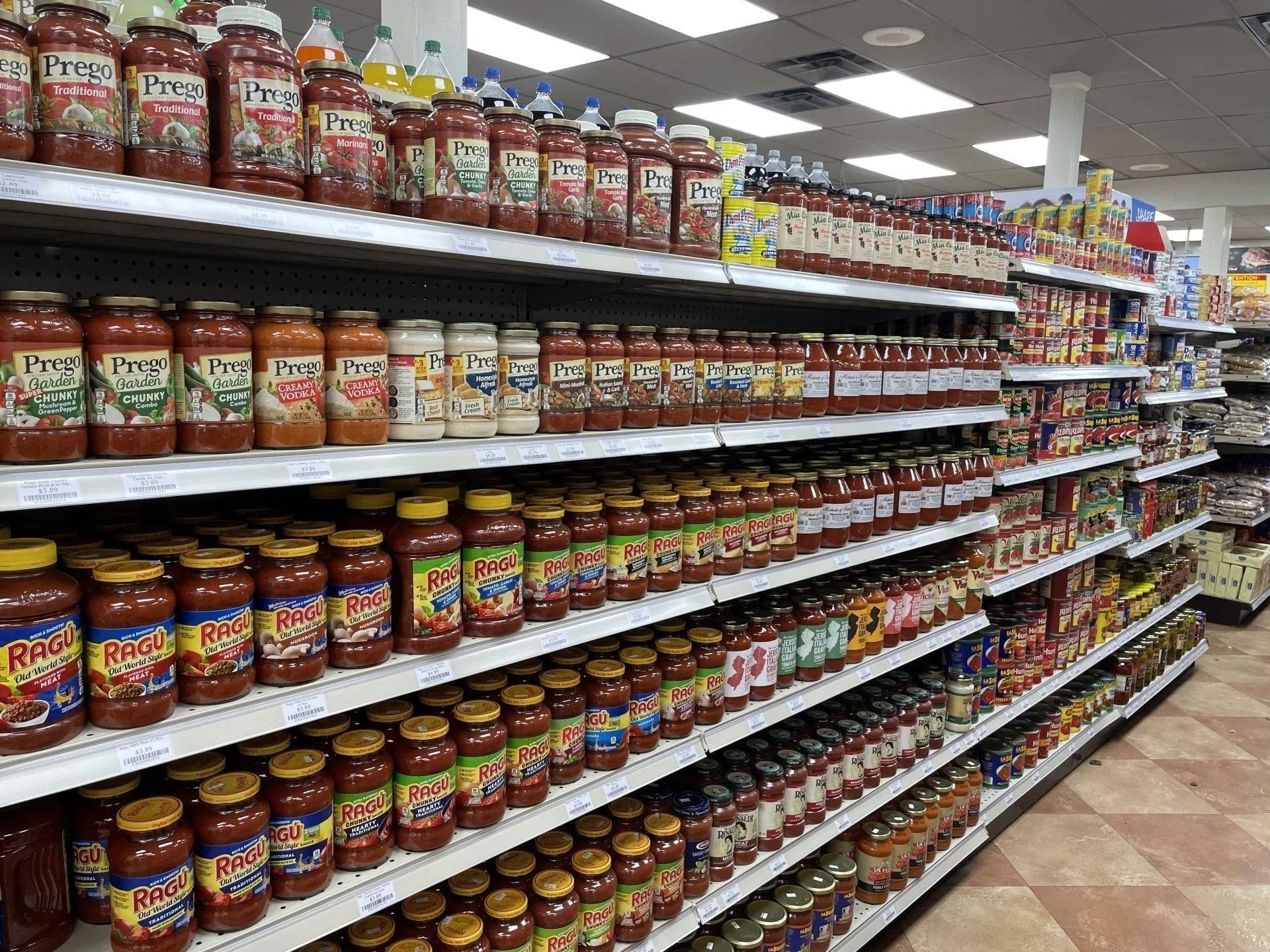 Shelves of pasta sauce jars in a grocery store aisle.