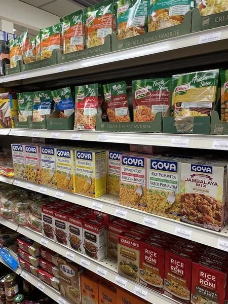 Shelves of various boxed and packaged rice products in a grocery store aisle.