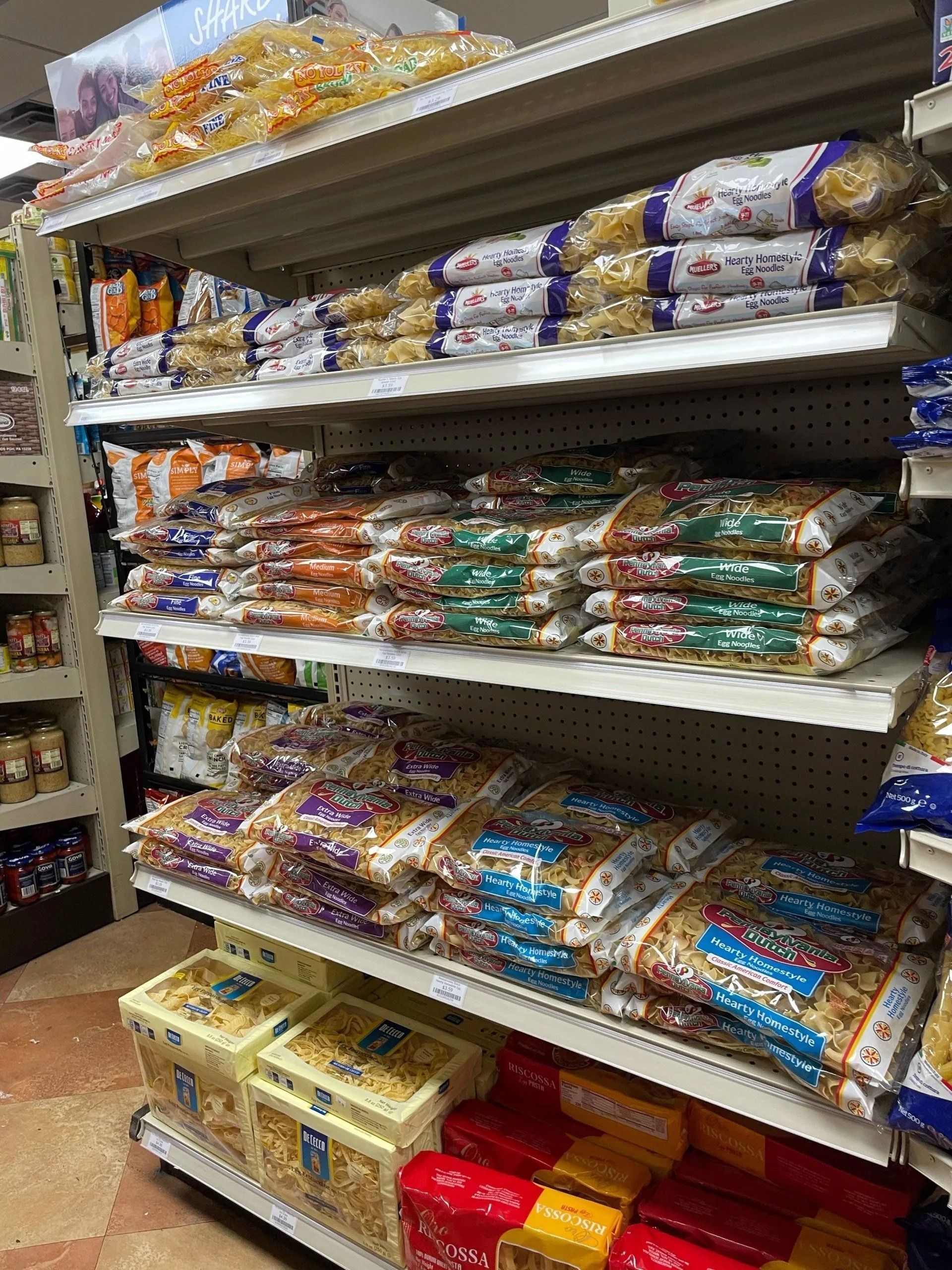 Shelves stocked with various pasta packages in a grocery store.