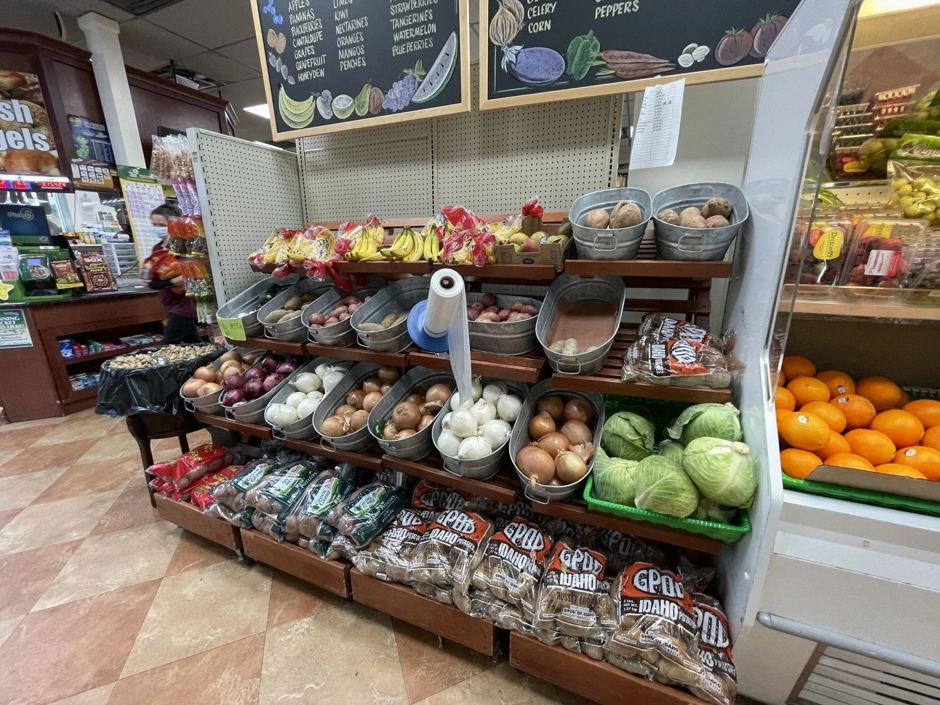 Produce section of a grocery store. Produce includes onions, potatoes, bananas, and oranges.