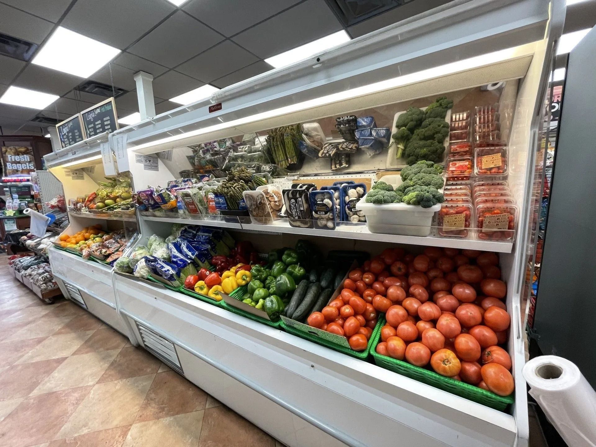 A refrigerated display case filled with produce in a grocery store.