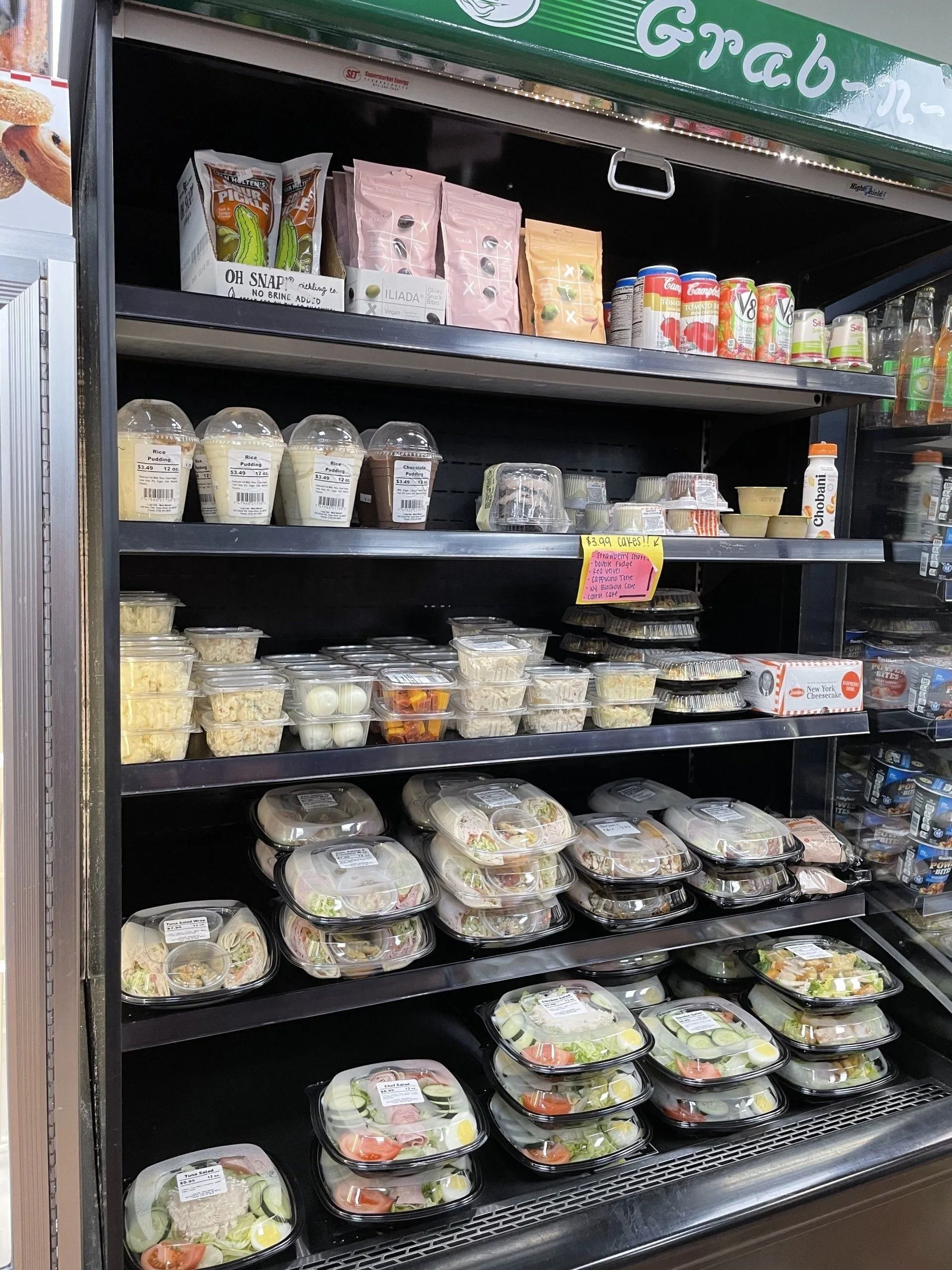 Refrigerated display case with pre-packaged salads and snacks for sale.