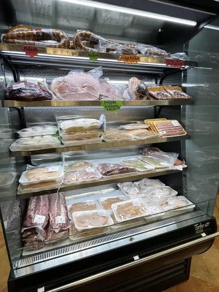 Meat products in a refrigerated display case. Packages of various meats on shelves.