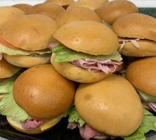 Tray of small sandwiches with meat, lettuce, and bun.