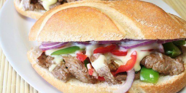 Sandwich with meat, red onion, peppers, and sauce.