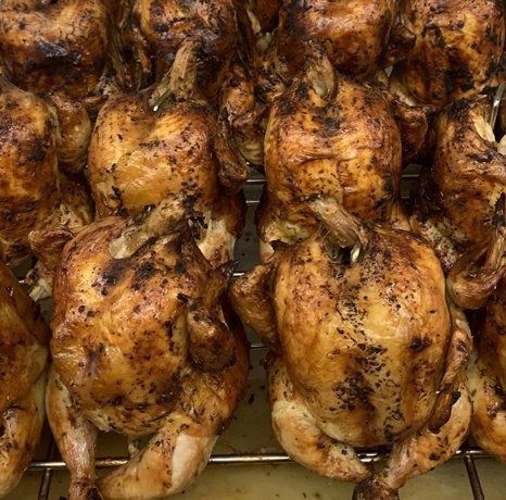 Roasted chickens on a rack, golden brown, with crispy skin.