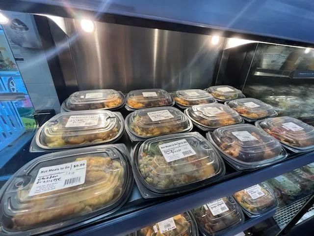 Prepared food containers in a refrigerated display case.