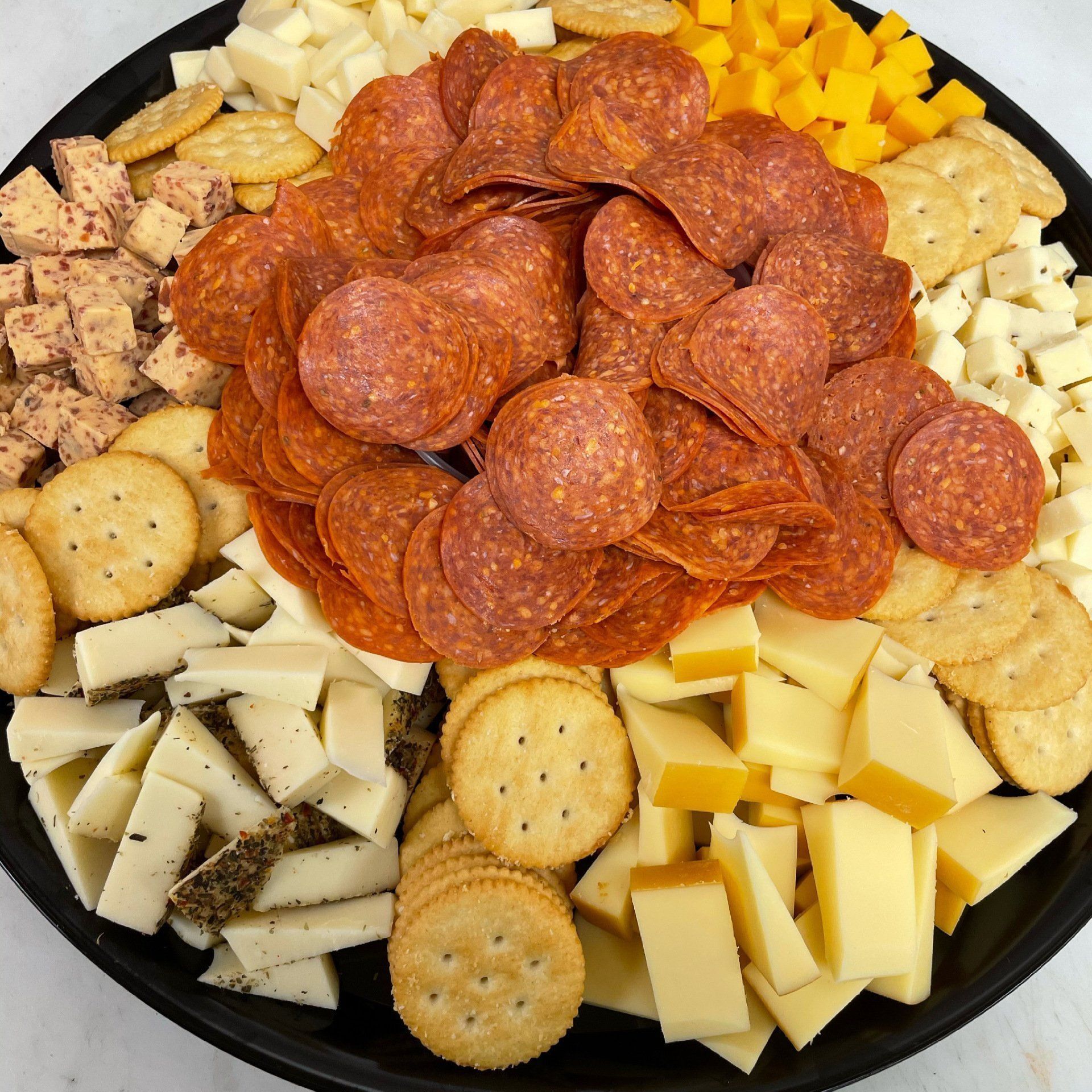 Charcuterie board with salami, crackers, and assorted cheeses.