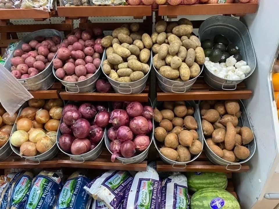Produce display: red potatoes, yellow potatoes, red onions, white onions, in metal bins.