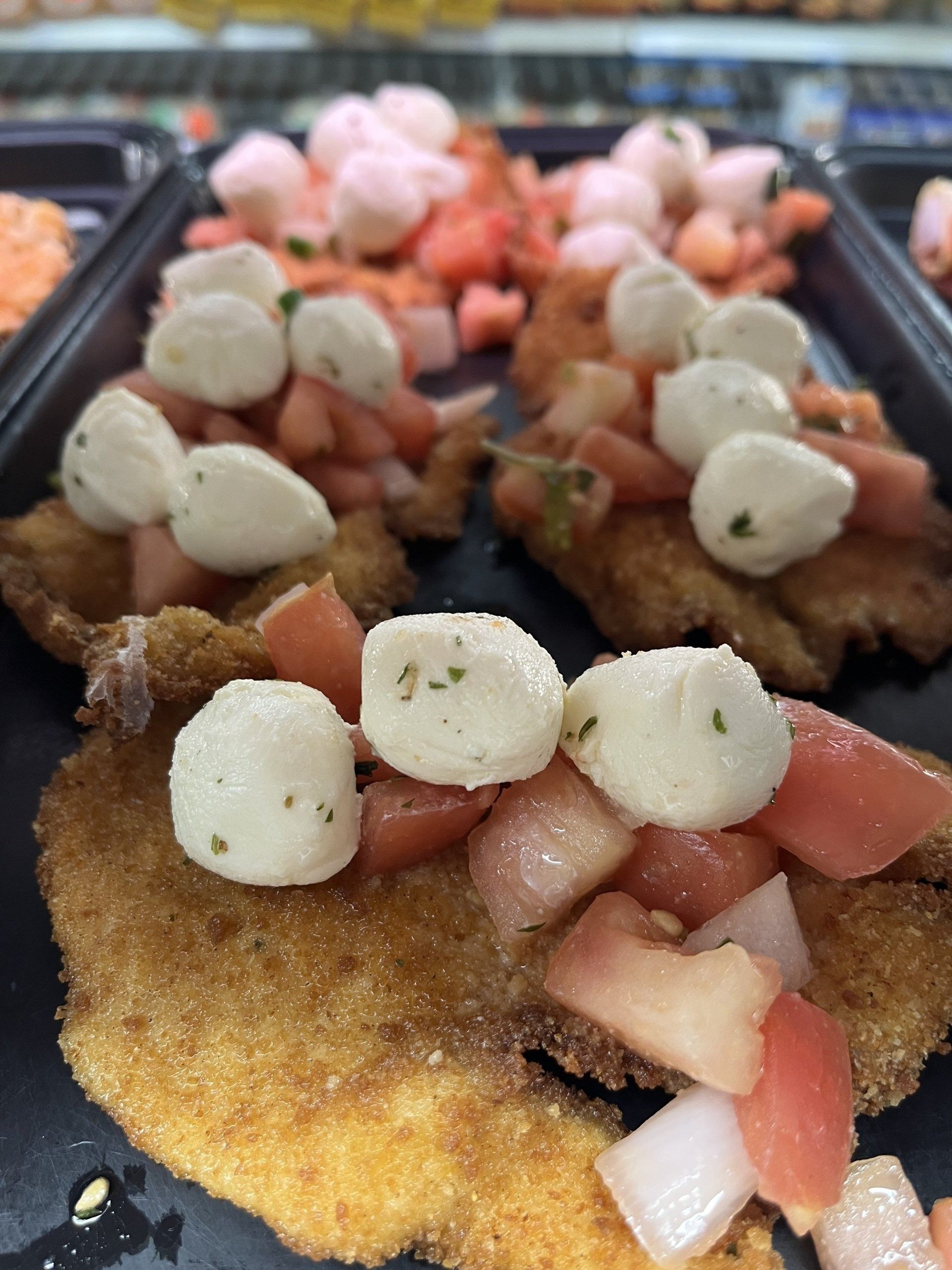 Breaded cutlets topped with diced tomatoes and mozzarella balls.