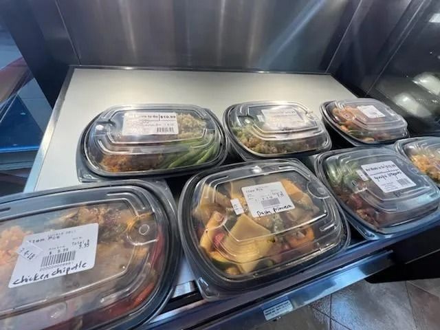Prepared food containers on display in a refrigerated case.