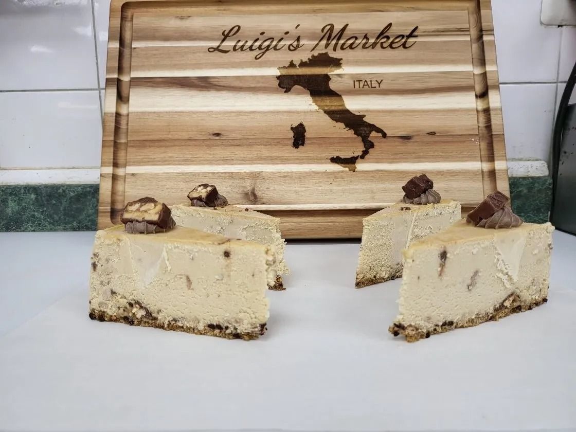 Cheesecake slices topped with candy, in front of a wooden cutting board engraved with the map of Italy and