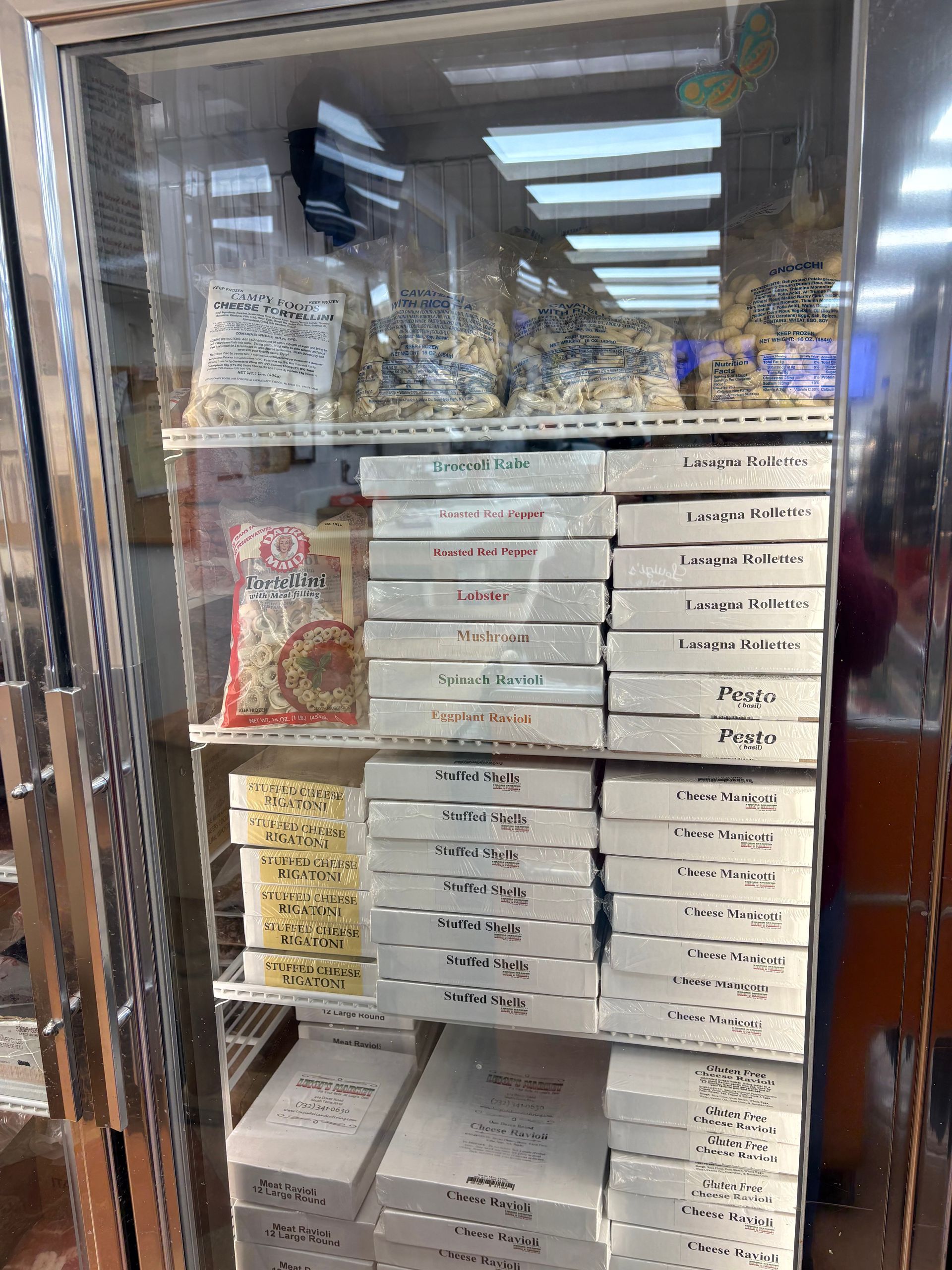 Display case filled with white boxes and clear bags of food items. Shelves are lit by overhead lights.
