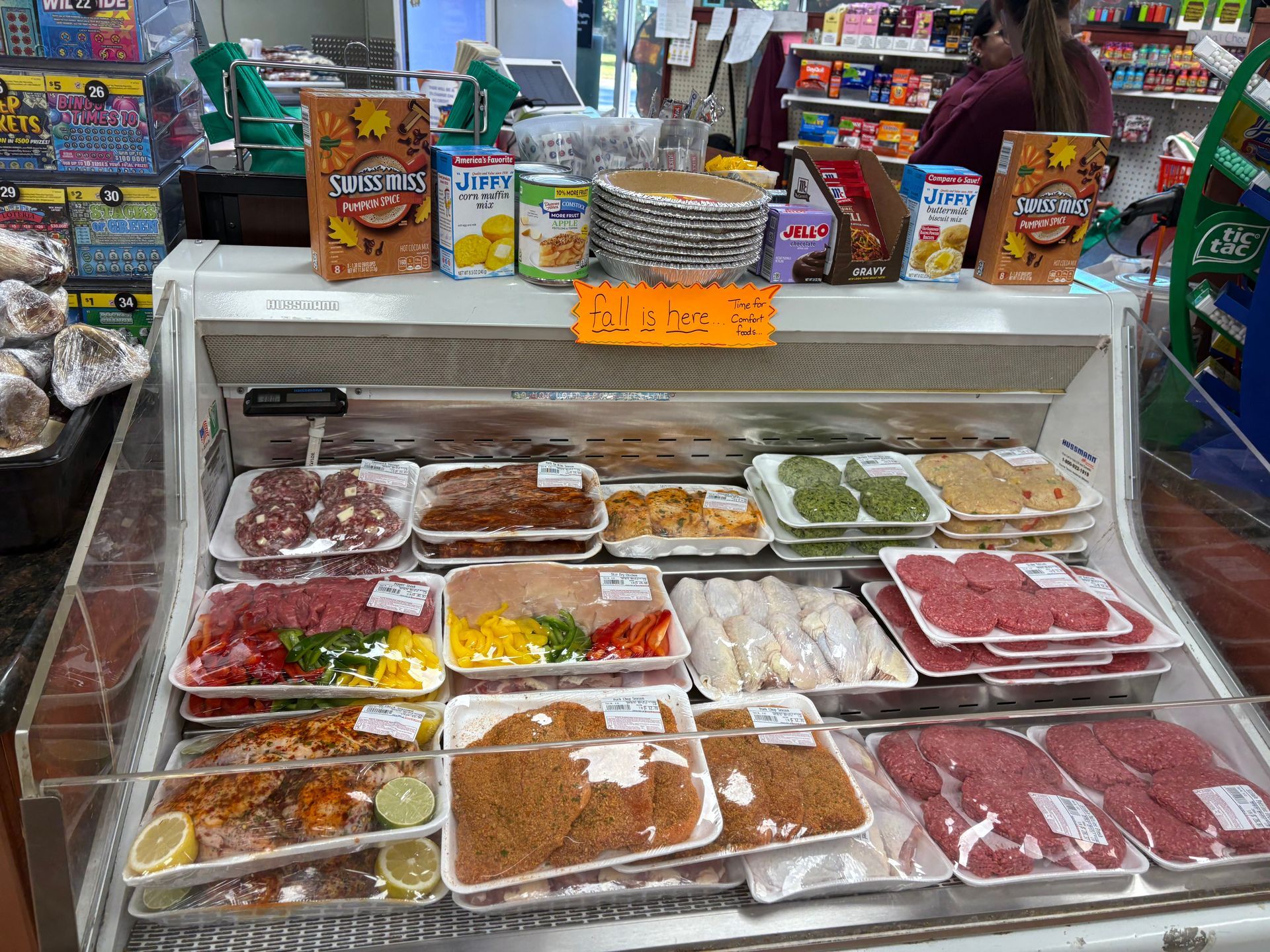 Coiled raw sausage in a black tray, close-up view showing the spiral shape and pink meat.