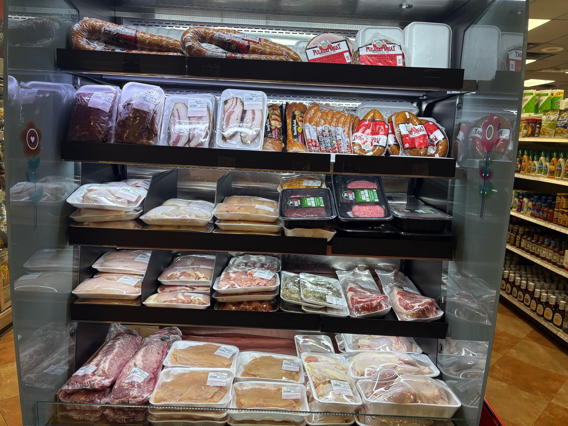 Meat display case in a grocery store, various packaged cuts of meat visible.