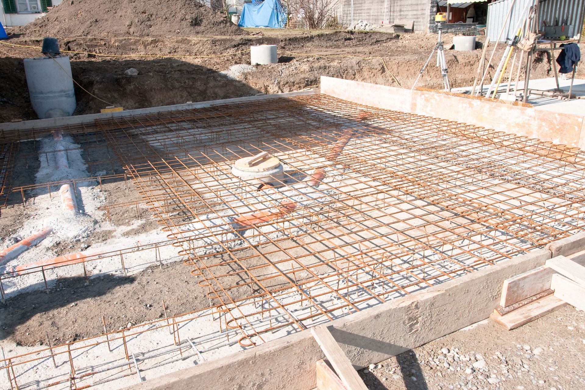 Construction site: exposed rebar grid on concrete foundation, ready for pouring.