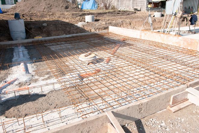 Construction site: exposed rebar grid on concrete foundation, ready for pouring.