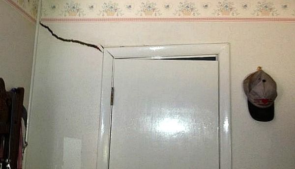 White door with a crack above it, baseball cap on the wall.