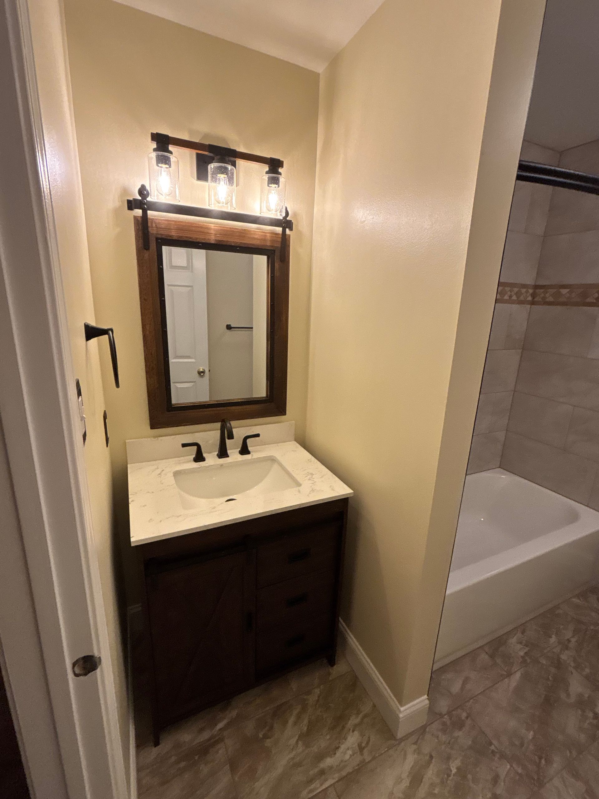 A bathroom with a sink , mirror and tub.