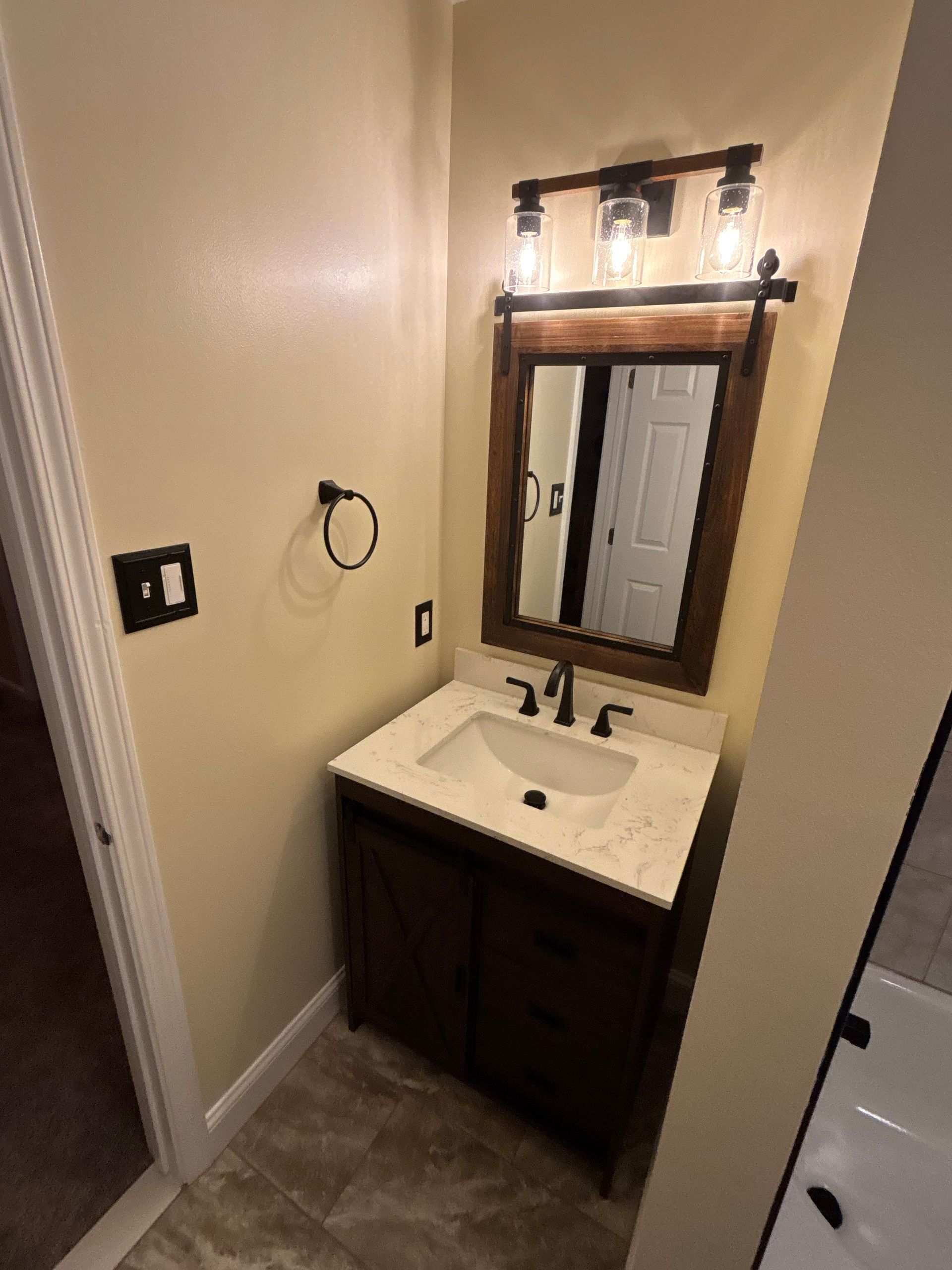A bathroom with a sink , mirror and light fixture.