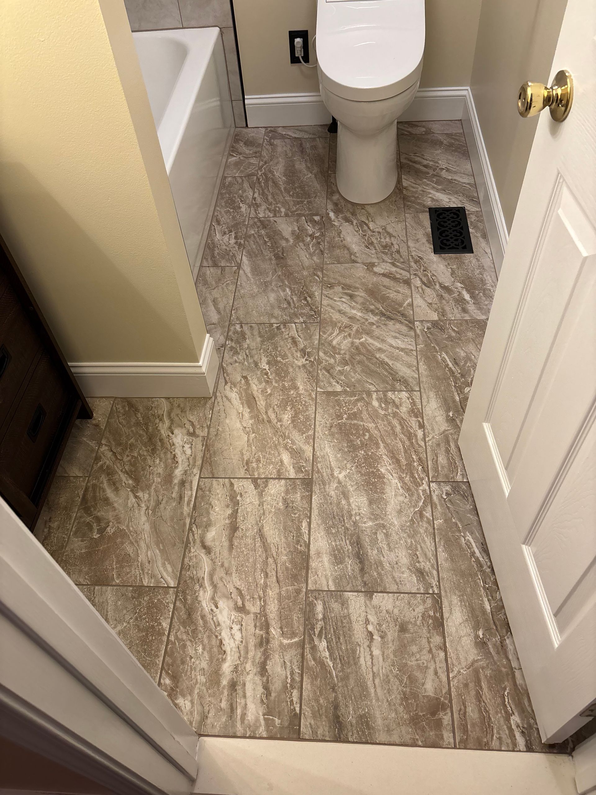 A bathroom with a toilet , bathtub and tile floor.