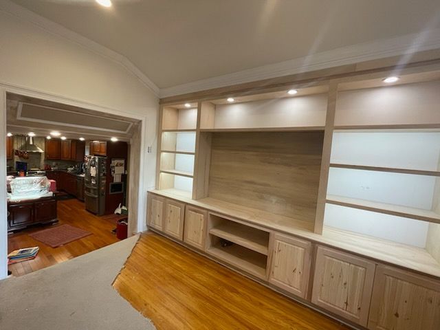 A living room with a large entertainment center and a kitchen in the background.