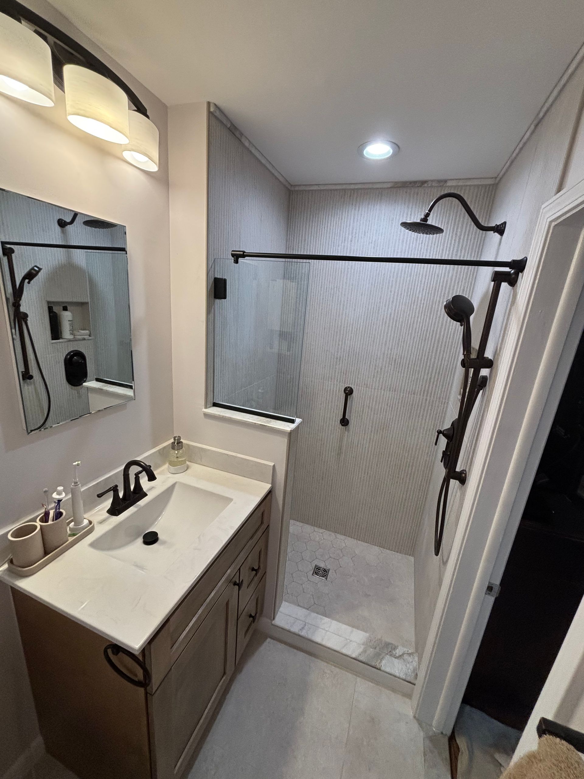 A bathroom with a sink and a walk in shower.
