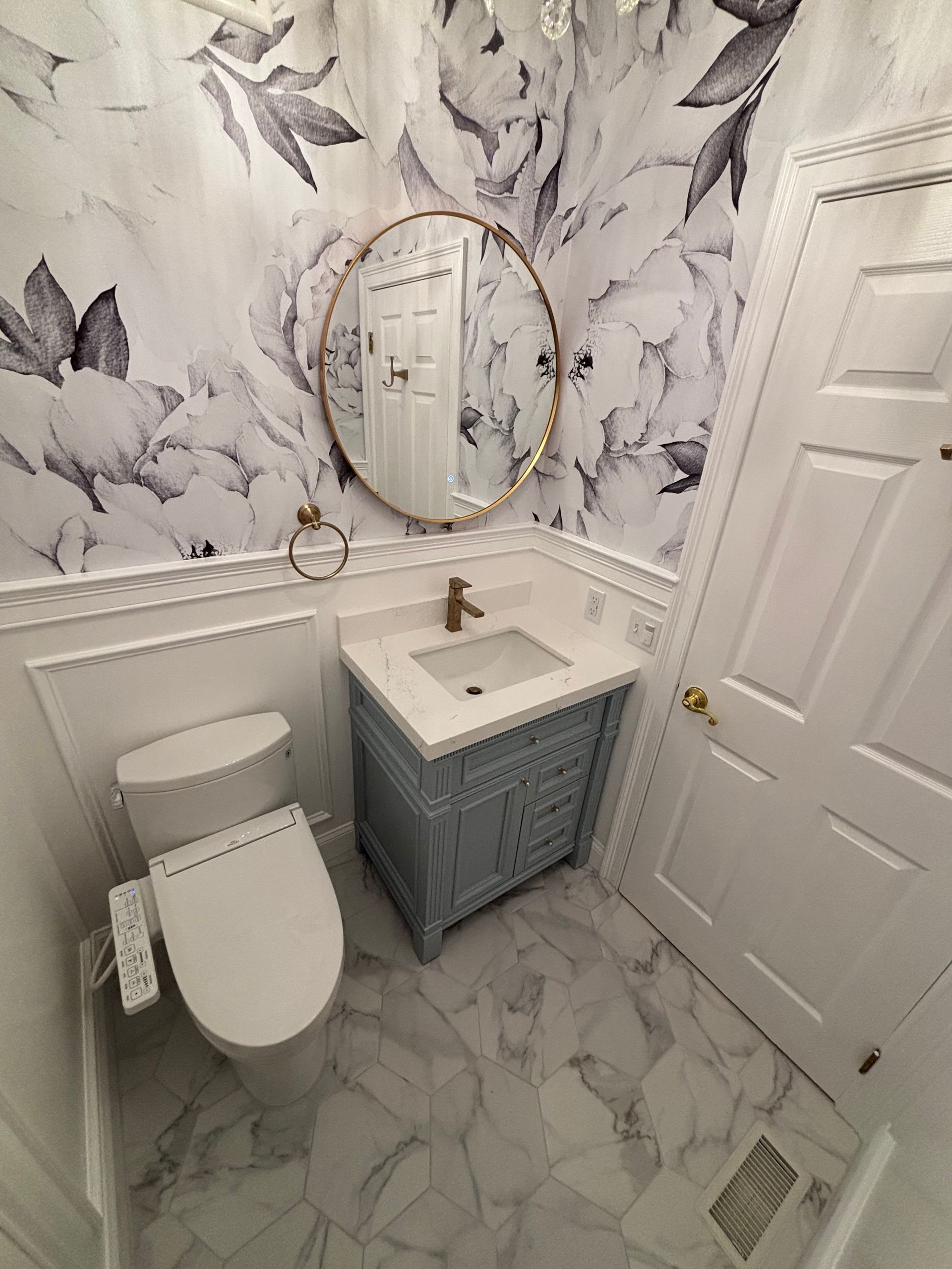 A bathroom with a toilet , sink and mirror.