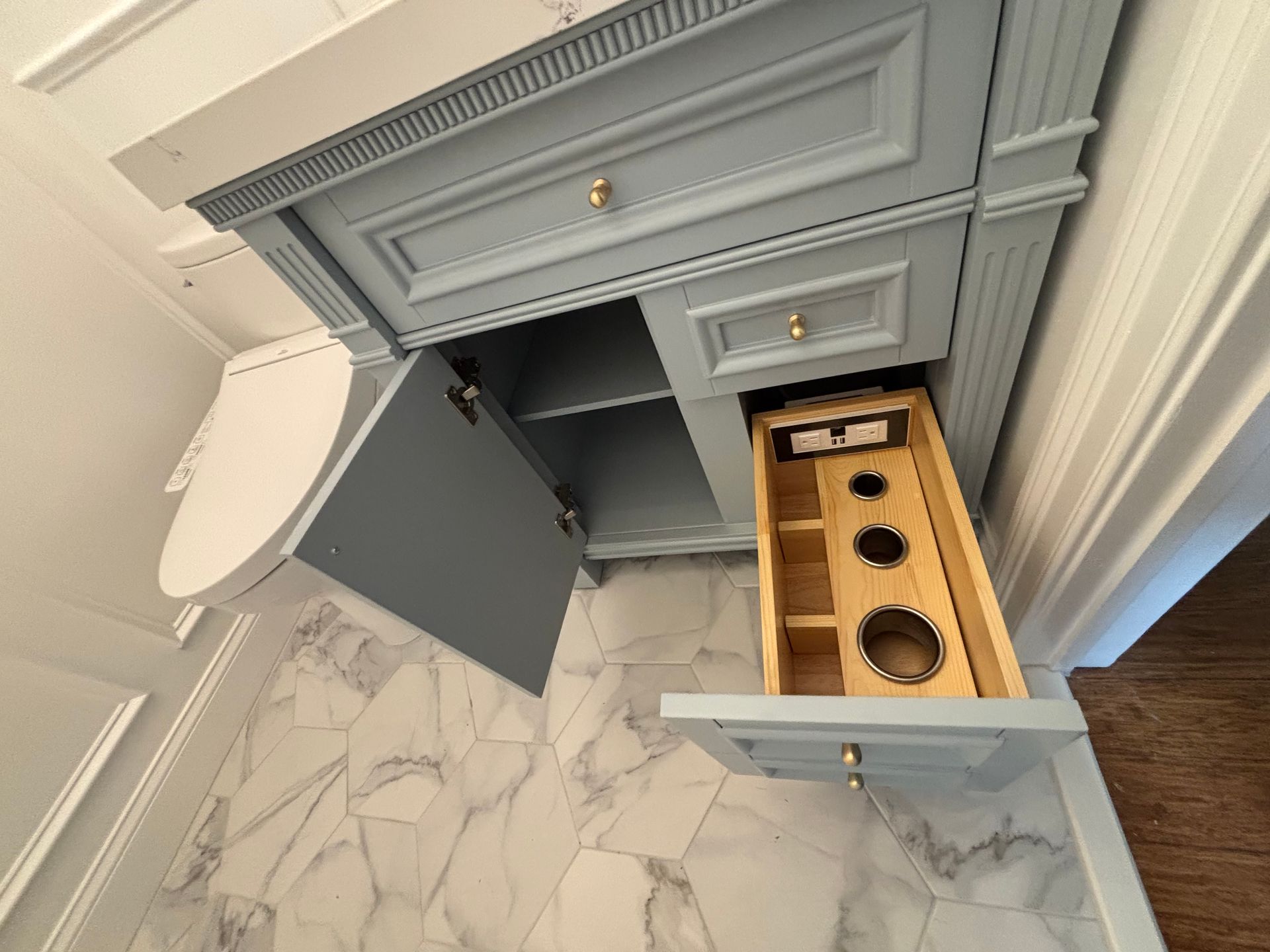 A bathroom vanity with a drawer open and a toilet in the background.